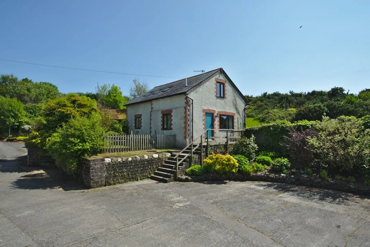 White-rendered holiday cottage against a blue sky, a North Devon cottage with sea views.