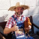 Family farm pictures of a man in a straw hat smiling and giving a thumbs up to the camera with a chicken under his arm.