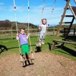 Family farm pictures of two young children playing on a swing set.