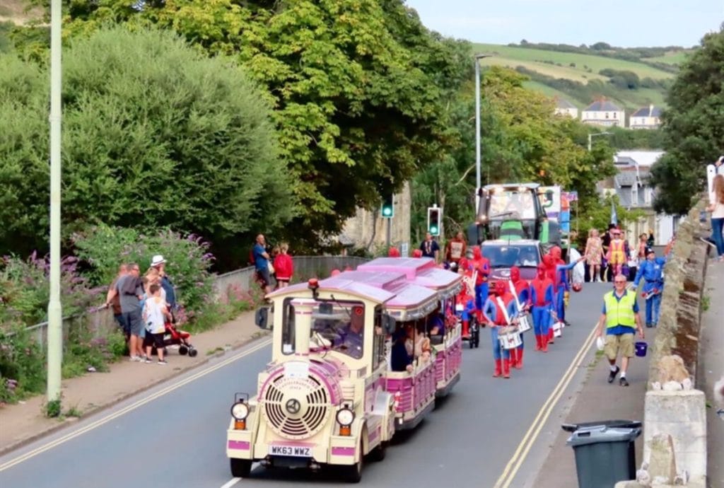 A range of carnival activities in Ilfracombe. A land train followed by a procession in costume.